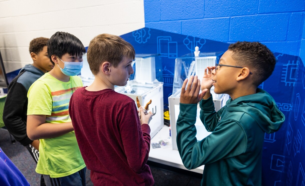 A photo of four students talking at the AWS Think Big Space in at J. Lupton Simpson Middle School in Leesburg, Virginia. 