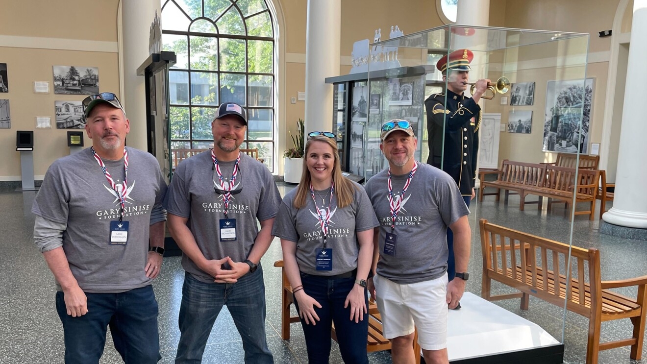 Amazon employees and Gary Sinise Foundation volunteers, Mike Waterman (Site Leader of MDT2), Zach Richardson (Assistant General Manager, CAE1), Charlotte La Belle (Principal, Global Military Affairs), and Donnie Hotchkiss (Sr. Operations Manager, CVG9) inside of the Arlington national Cemetery [Left to Right].