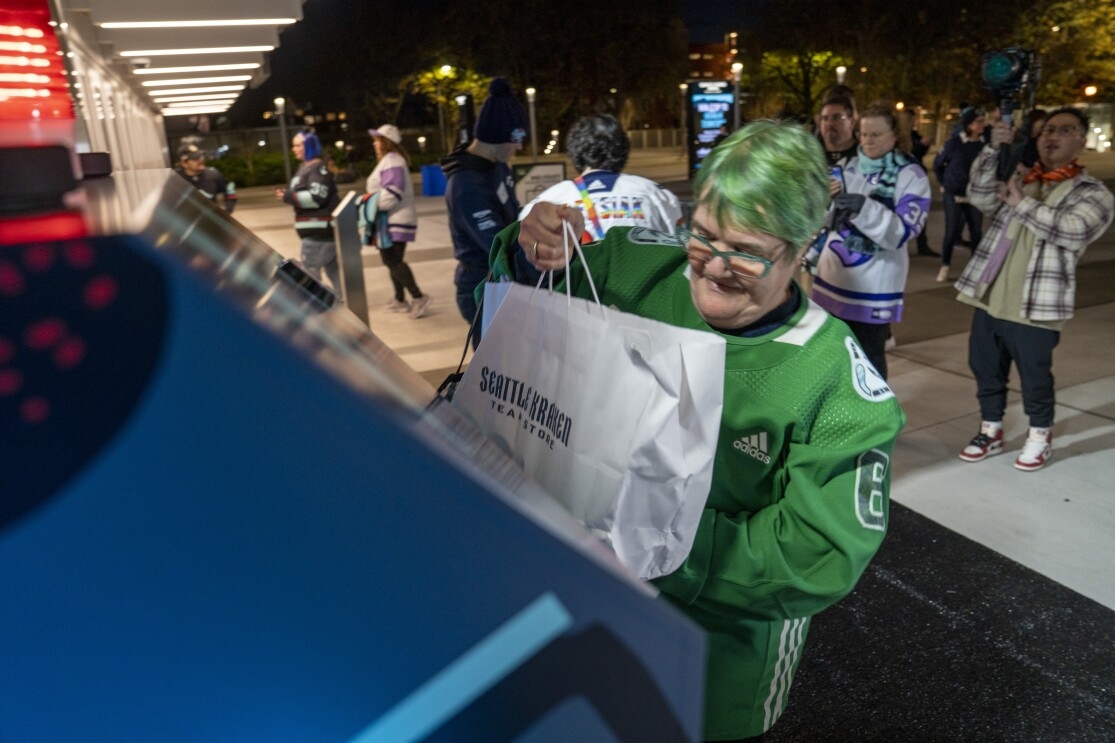 Someone donating canned goods outside of the Climate Pledge Arena in support of the 'Together to End Hunger' food drive