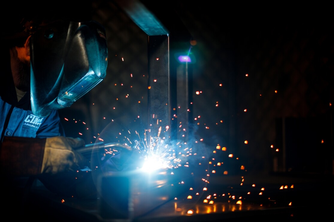 Sparks fly as a worker in safety gear uses welding equipment.