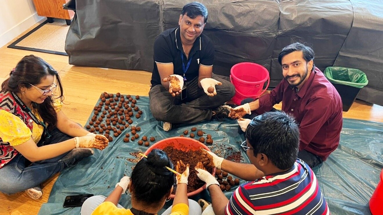 A group of volunteers sit in a circle and make seed balls.