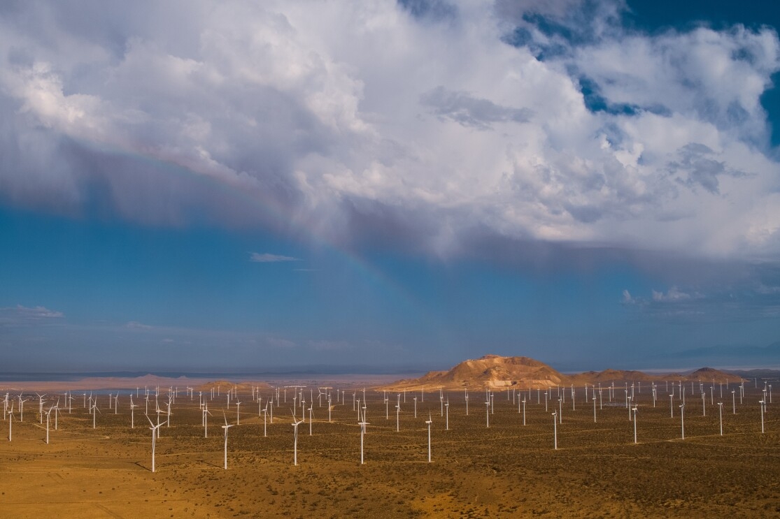 An aerial view of wind farm in a mountainous desert landscape.