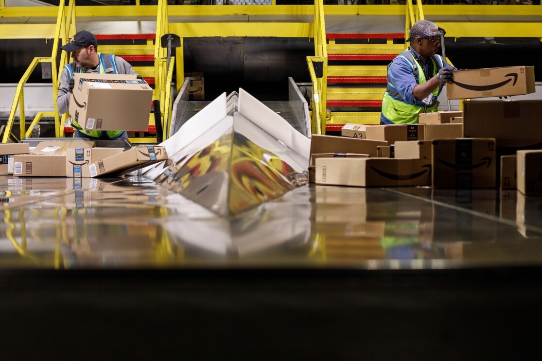 Two Amazon associates handle packages at an Amazon fulfillment center, PIT5, in Pittsburgh, PA