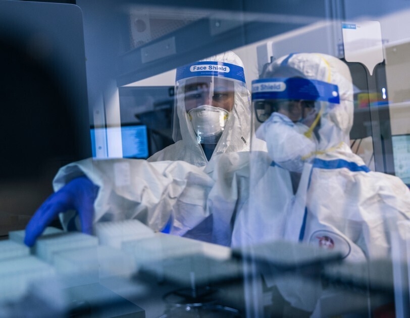 Two people in PPE look at lab samples.