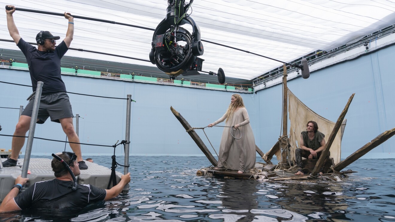 Behind-the-scenes view of a man and woman sailing on a scrappy boat.