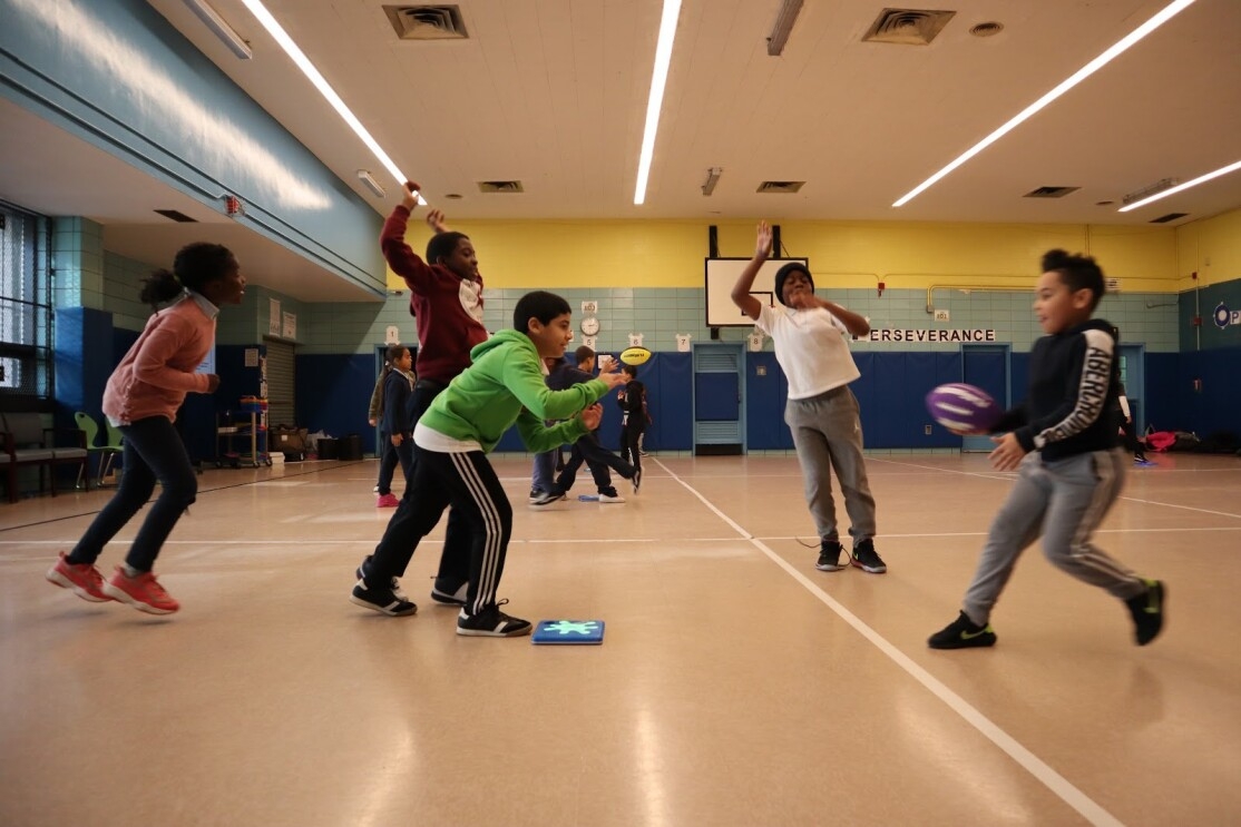 An image of children playing the game, Splat. They're jumping on small blue squares that react when they jump. 