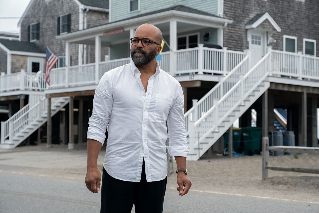 Actor Jeffrey Wright standing on a street in front of several homes looking off into the distance. He is on the set for American Fiction.
