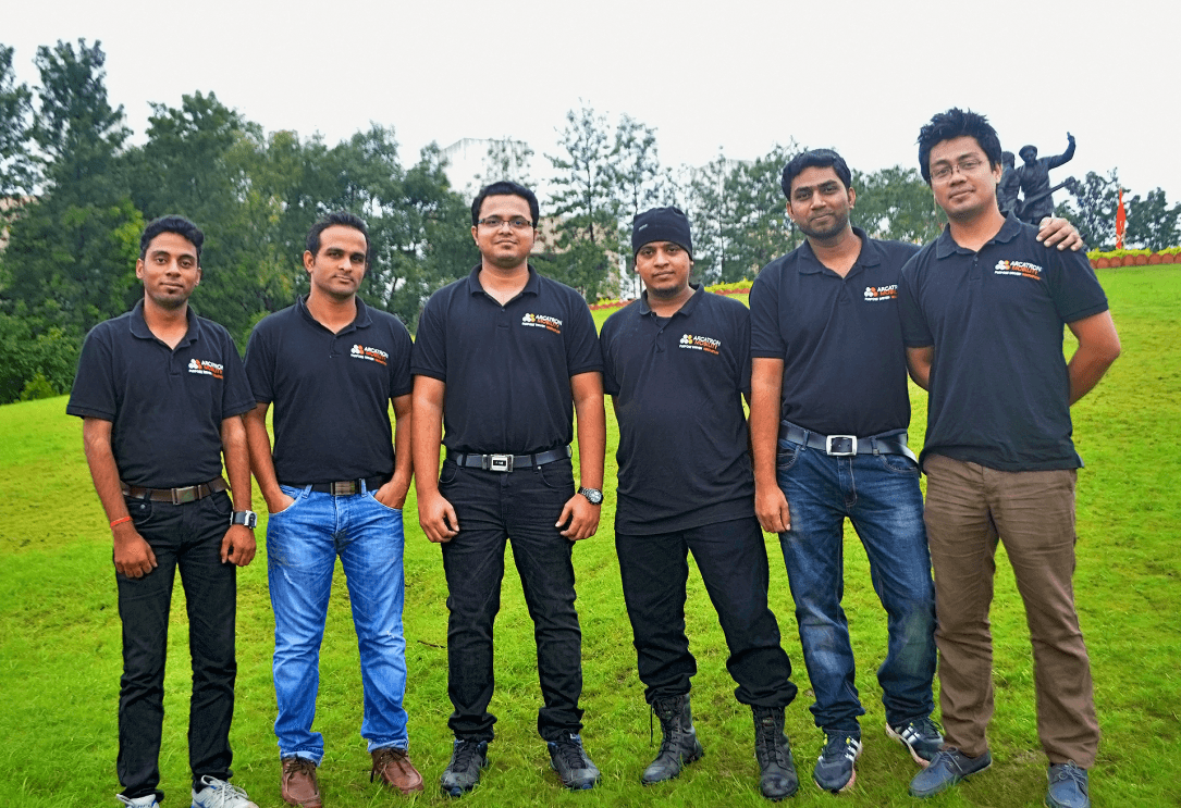 The team that makes up Arcatron stands outside and smiles for the camera. The team is six men and they are wearing Arcatron polo shirts.