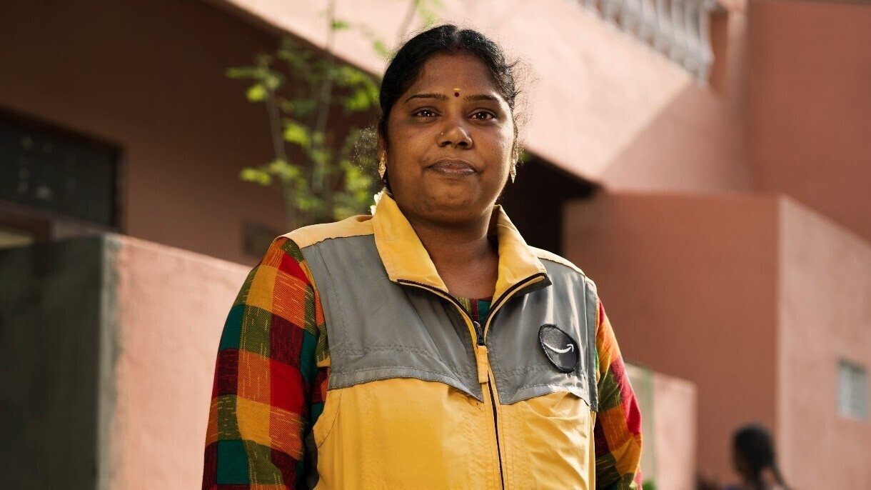 Keerthika wears a yellow Amazon vest and stands outside.