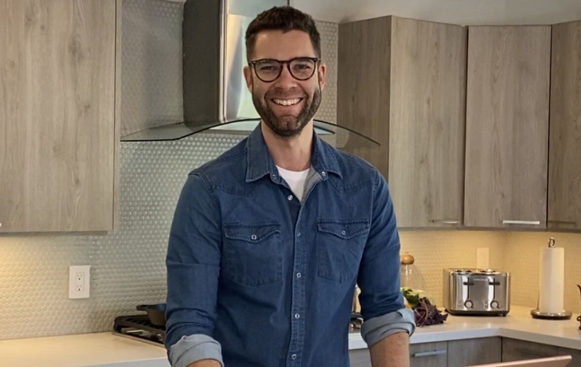 An image of Alexander E., Founder & CEO of Prepdeck, standing in a kitchen while smiling for a photo.