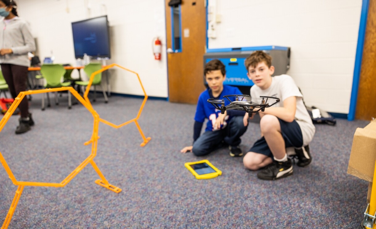 A photo of two students operating a drone at the AWS Think Big Space in Leesburg, Virginia. 