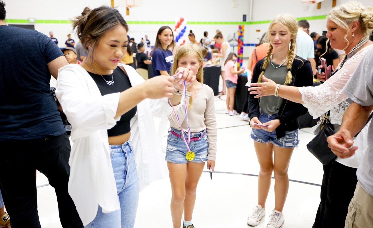 Suni Lee poses with students at an elementary school.