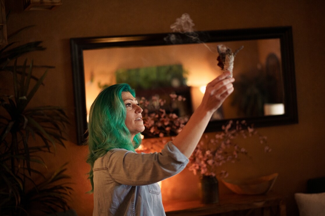 Smoke rises from a bundle that a woman is holding aloft.