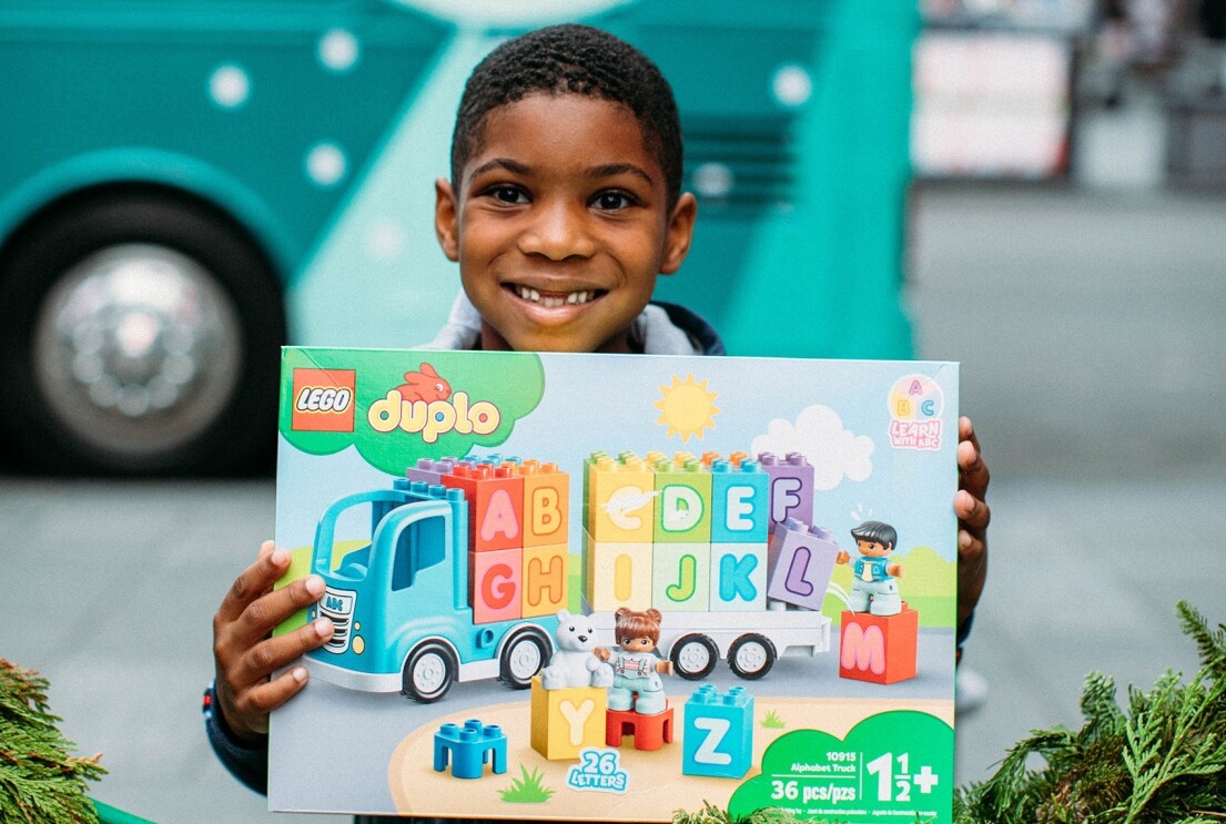 An image of a young boy smiling and holding a building blocks set.