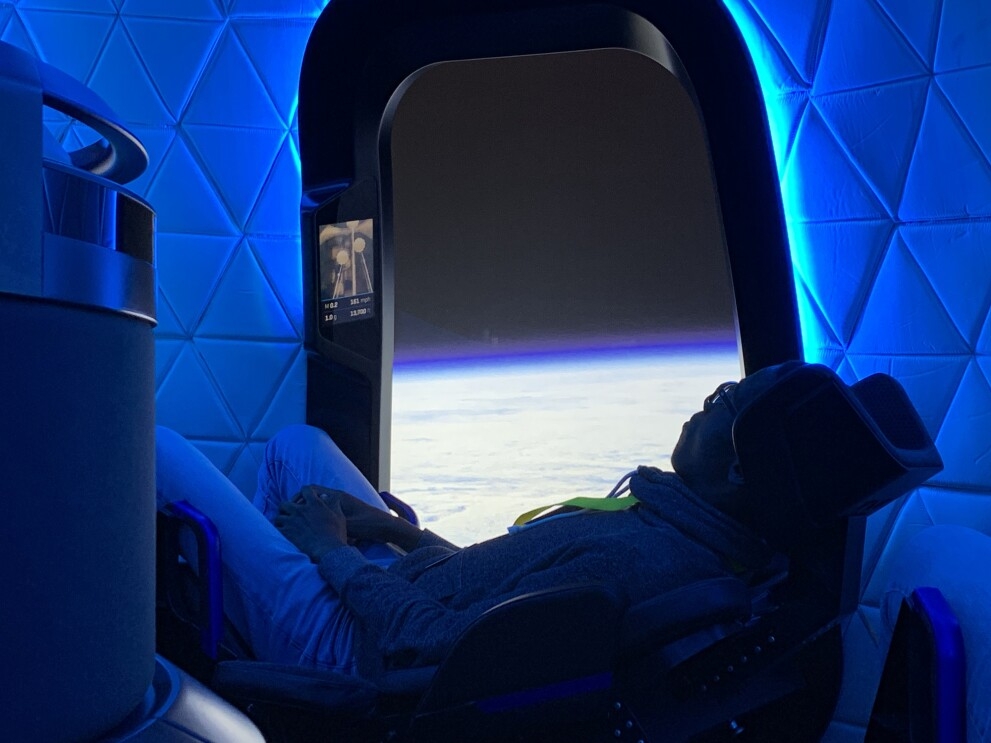 A teen lounges in a seat within the Blue Origin capsule.
