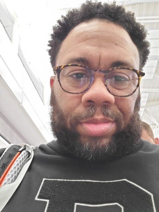 A close up photograph of a man with a beard wearing glasses.