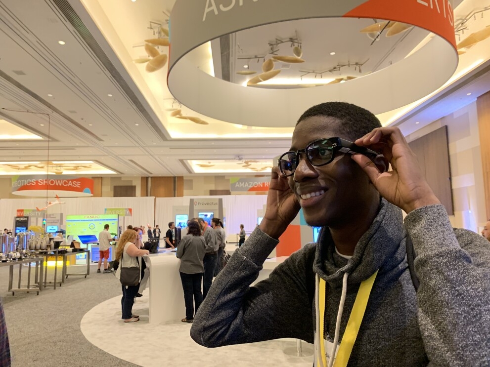 A teen smiles, as he tries on North smart glasses, inside a conference hall.