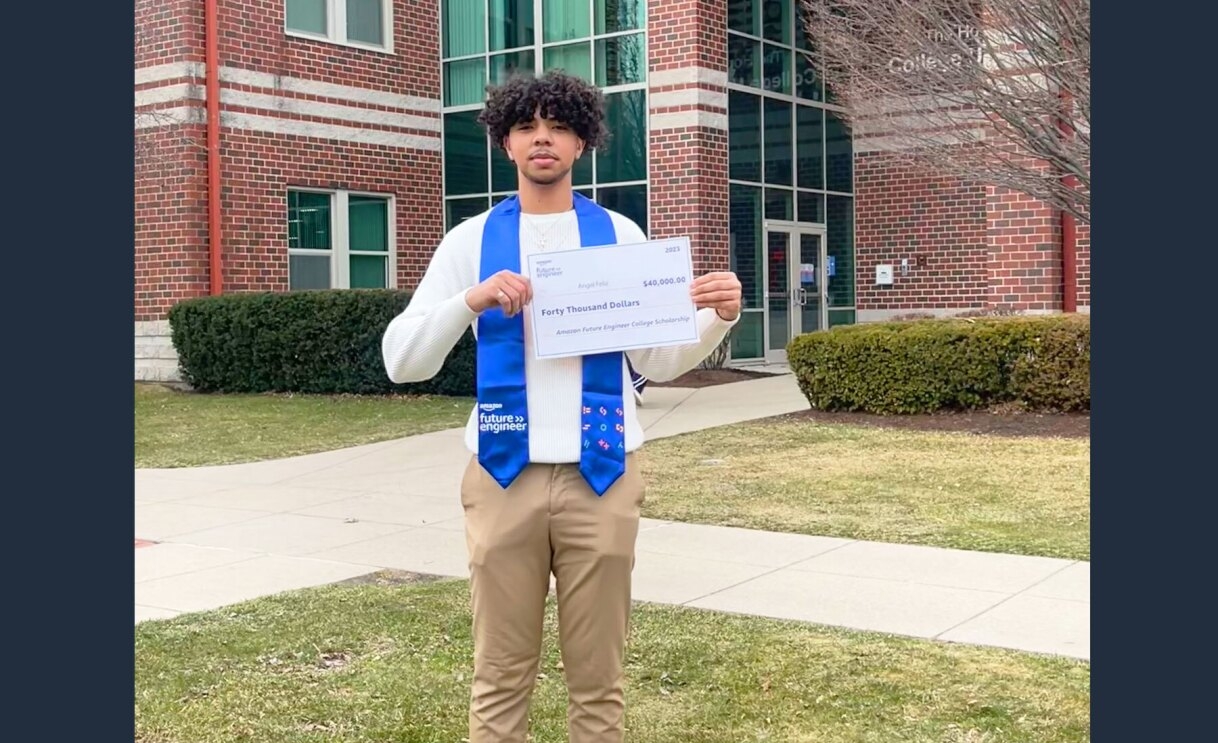 An image of Angel Feliz, a 2023 Amazon Future Engineer Scholarship recipient, holding out a check for his scholarship fund.