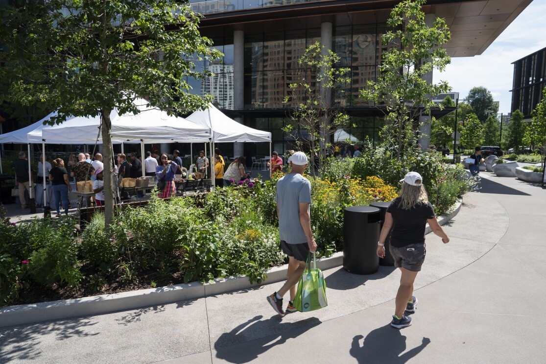 Individuals walking past the opening of the Met Park’s Butterfly Garden