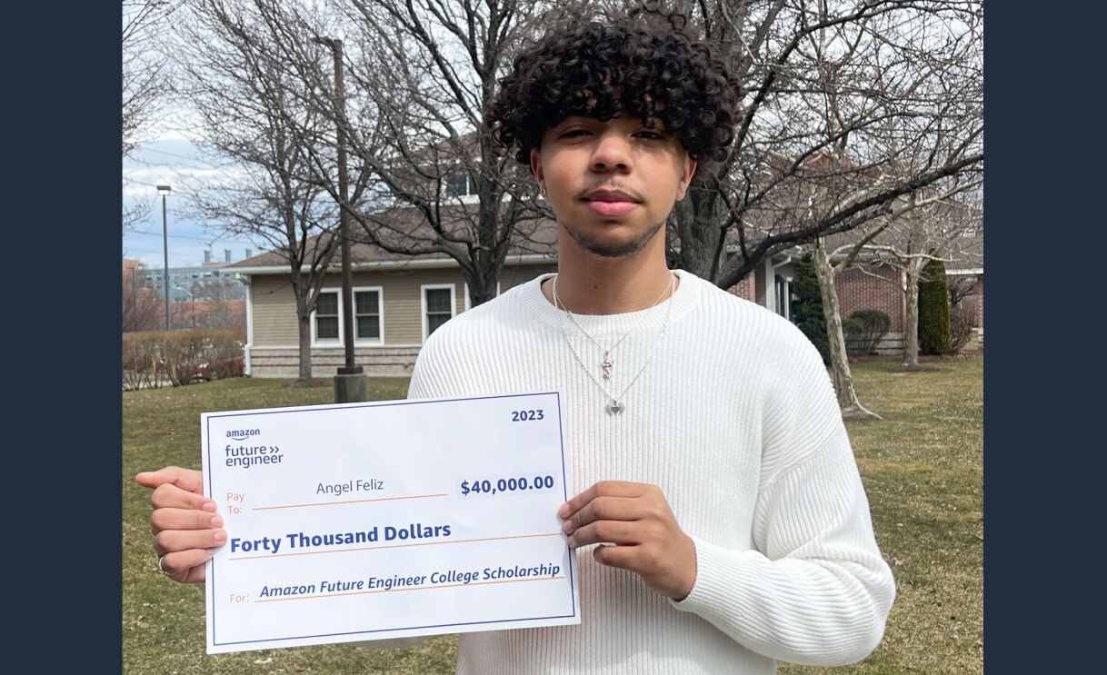 An image of Angel Feliz, a 2023 Amazon Future Engineer Scholarship recipient, holding out his fund check.