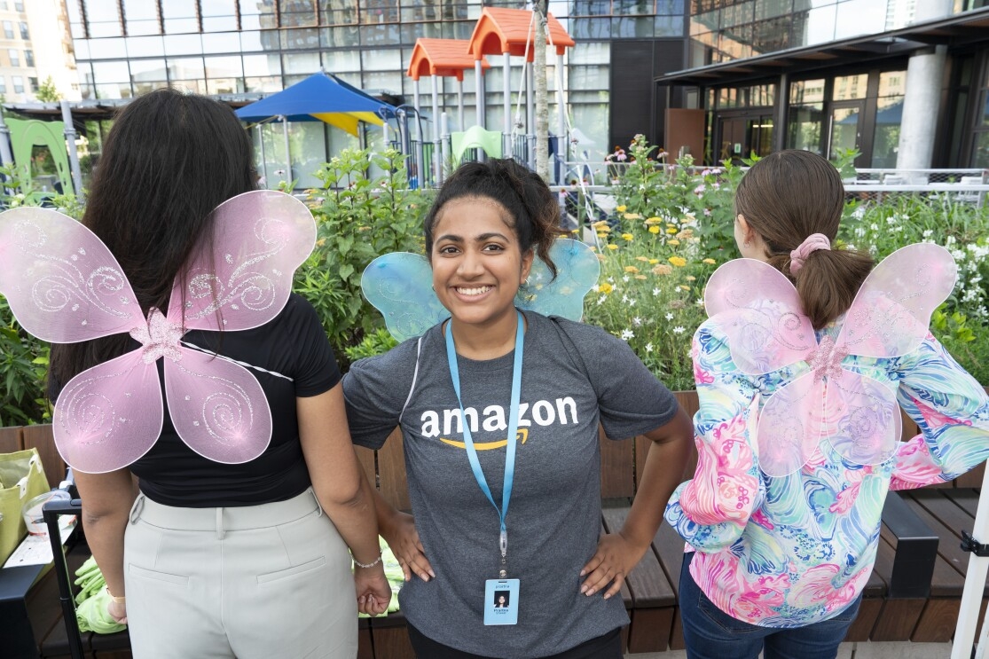 An Amazon employee in between two Amazon employees with butterfly wings on their back facing the opposite direction