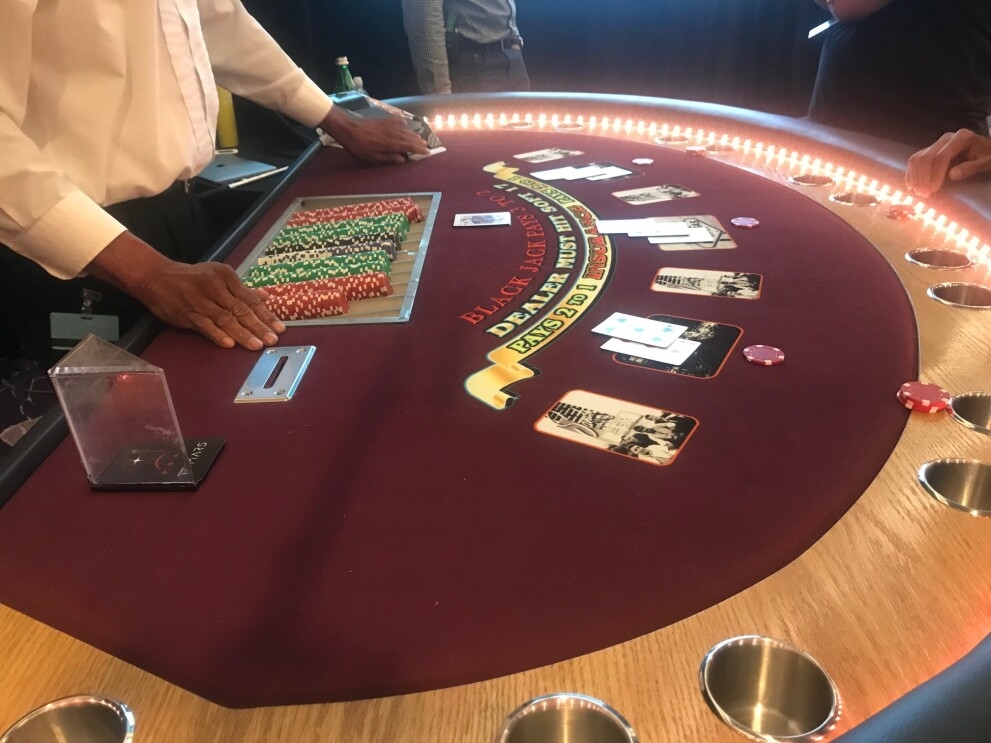 A blackjack dealer plays against three users who designed a machine learning algorithm to play the game.