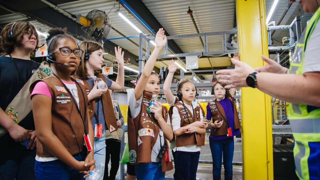 An image of Girl Scouts touring an Amazon fulfillment center.