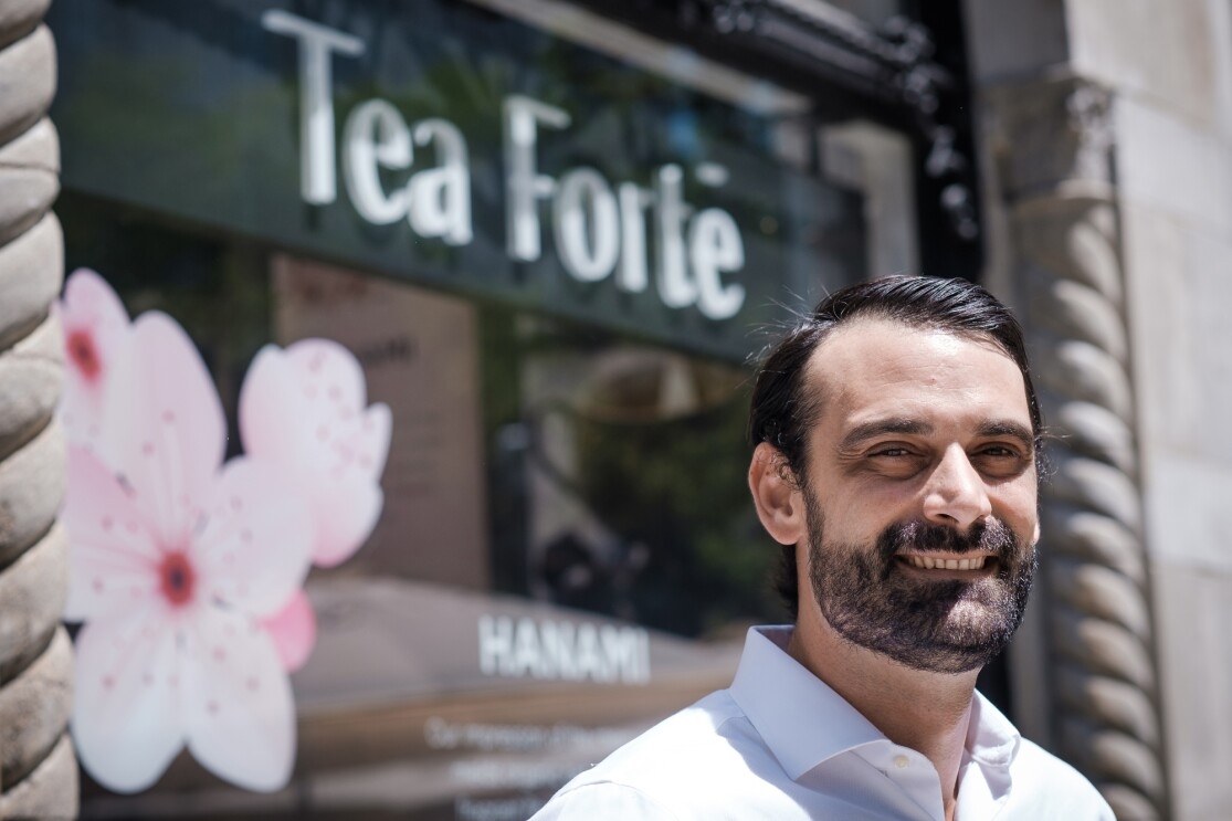 A man stands in front of a storefront bearing a sign that says "Tea Forté."