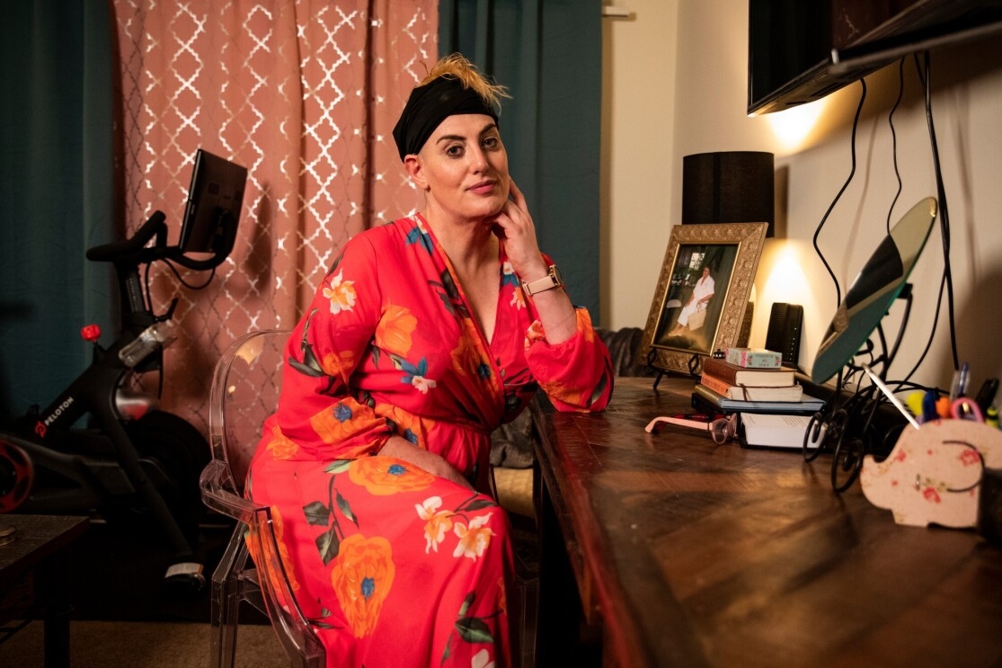 Luv-Luv, a fulfillment center employee, sits in her home smiling for a photo in a pink dress. 