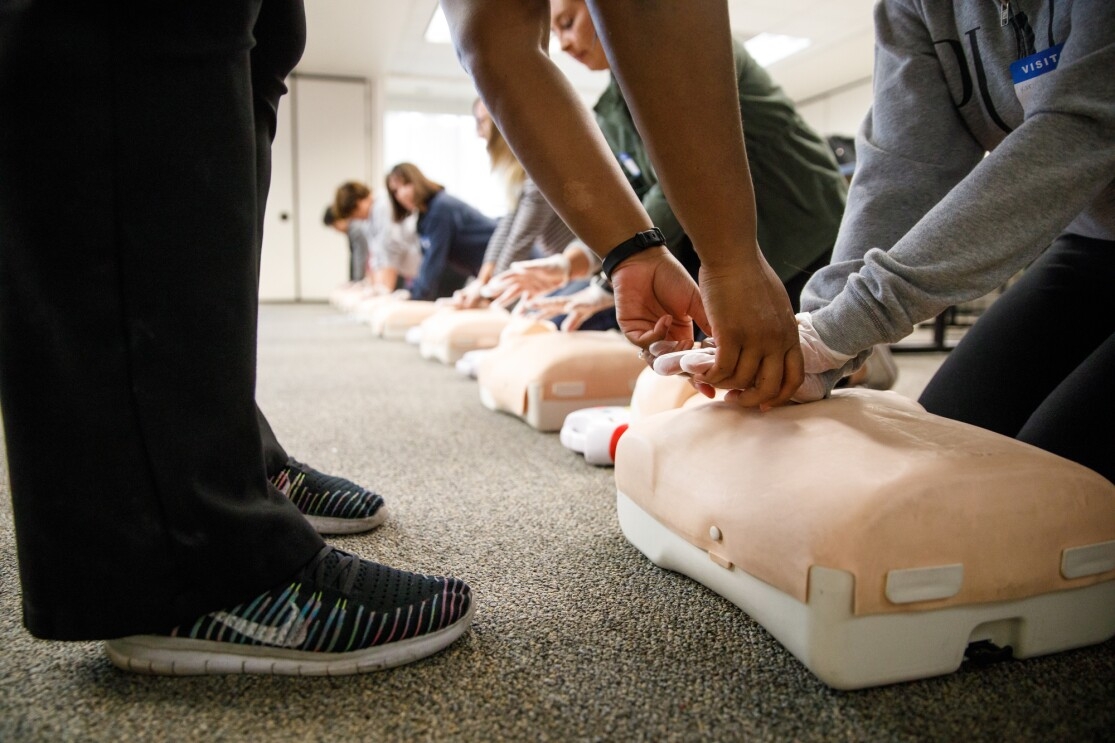 CPR instructor Jamie Davis helps a student learn how to do chest compressions