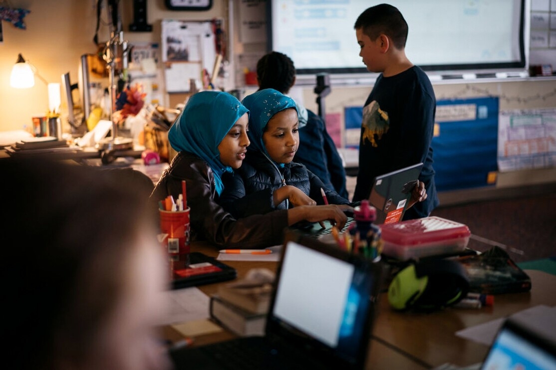 Two students in hijabs study coding at an Amazon-provided laptop