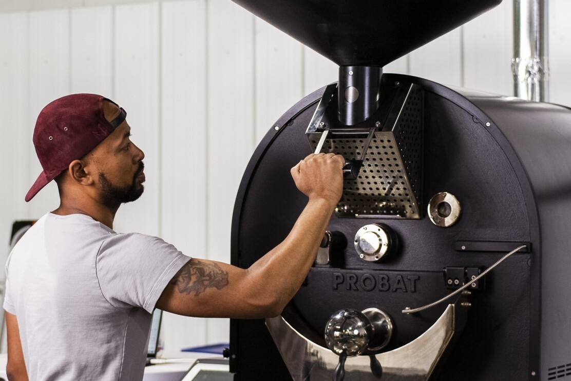 A man operating a coffee roasting machine.