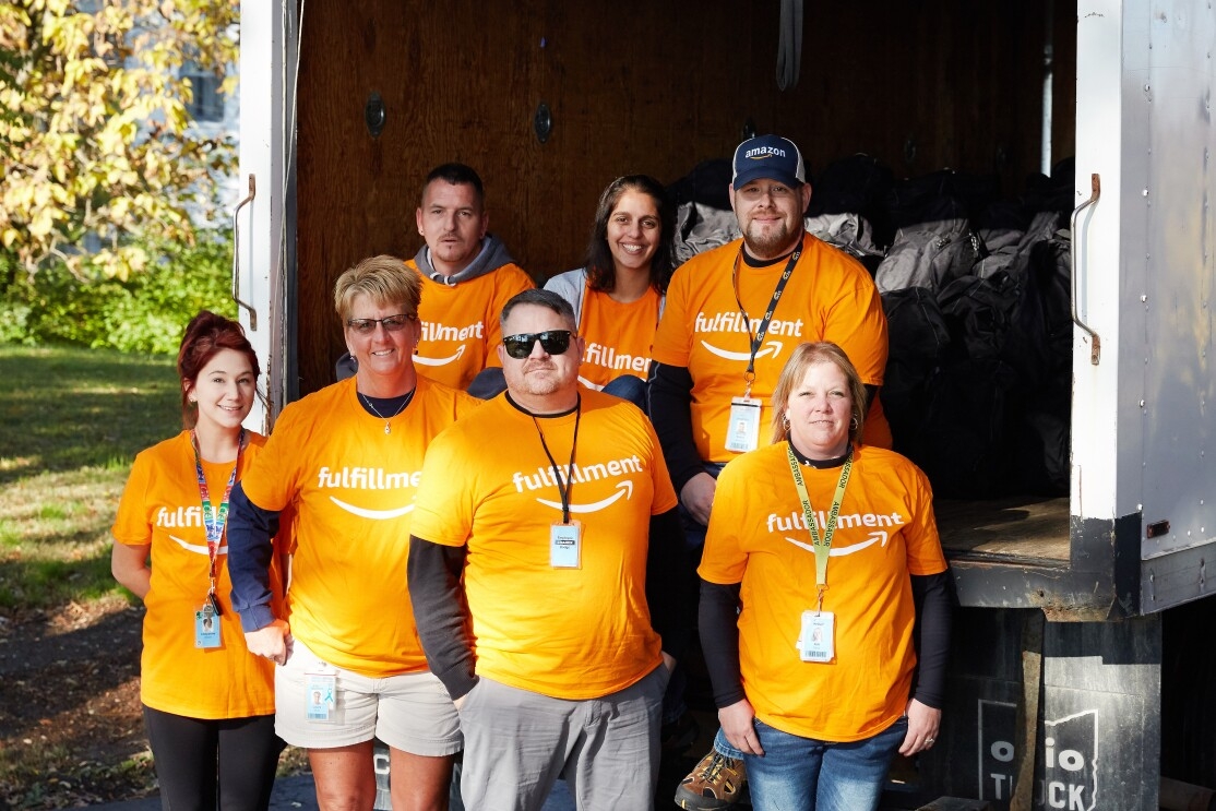 Amazon Fulfillment associates gathered to stuff backpacks with essentials