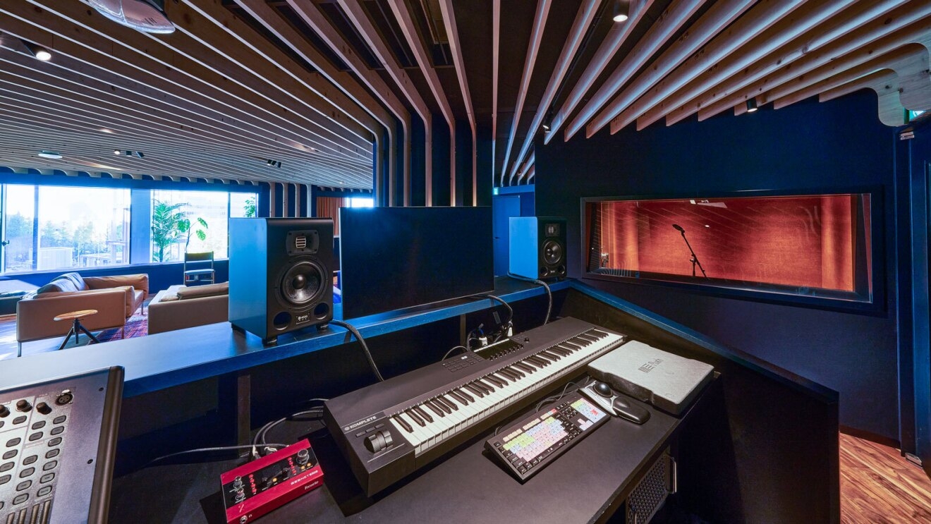 The recording studio at the Amazon Music creator space in Tokyo. There is a desk with a piano keyboard, a monitor, a speaker, and other sound controls.