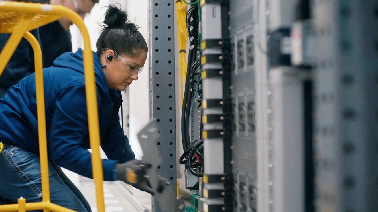 A photo of Tasha Engum fixing equipment in an AWS data center.