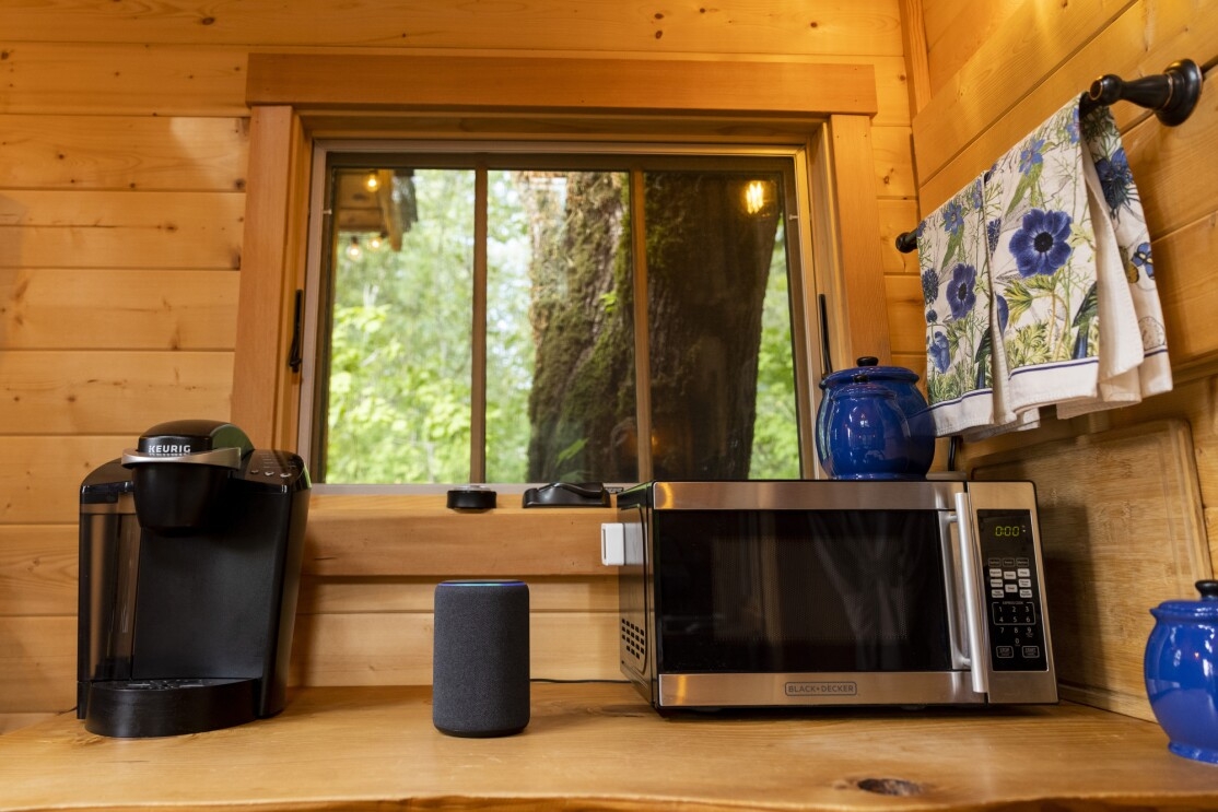 An Amazon Echo on a counter with a microwave and coffeemaker. 
