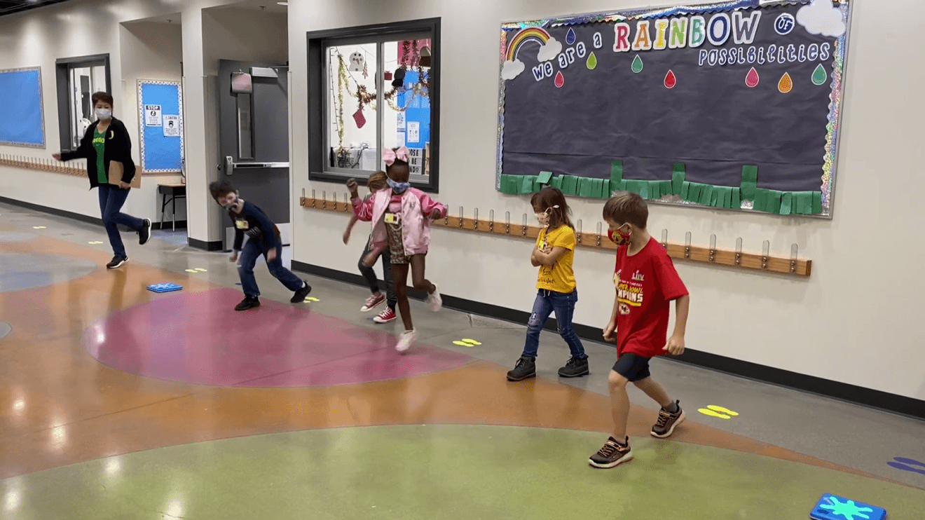 An image of children playing the game, Splat. They're jumping on small blue squares that react when they jump. 