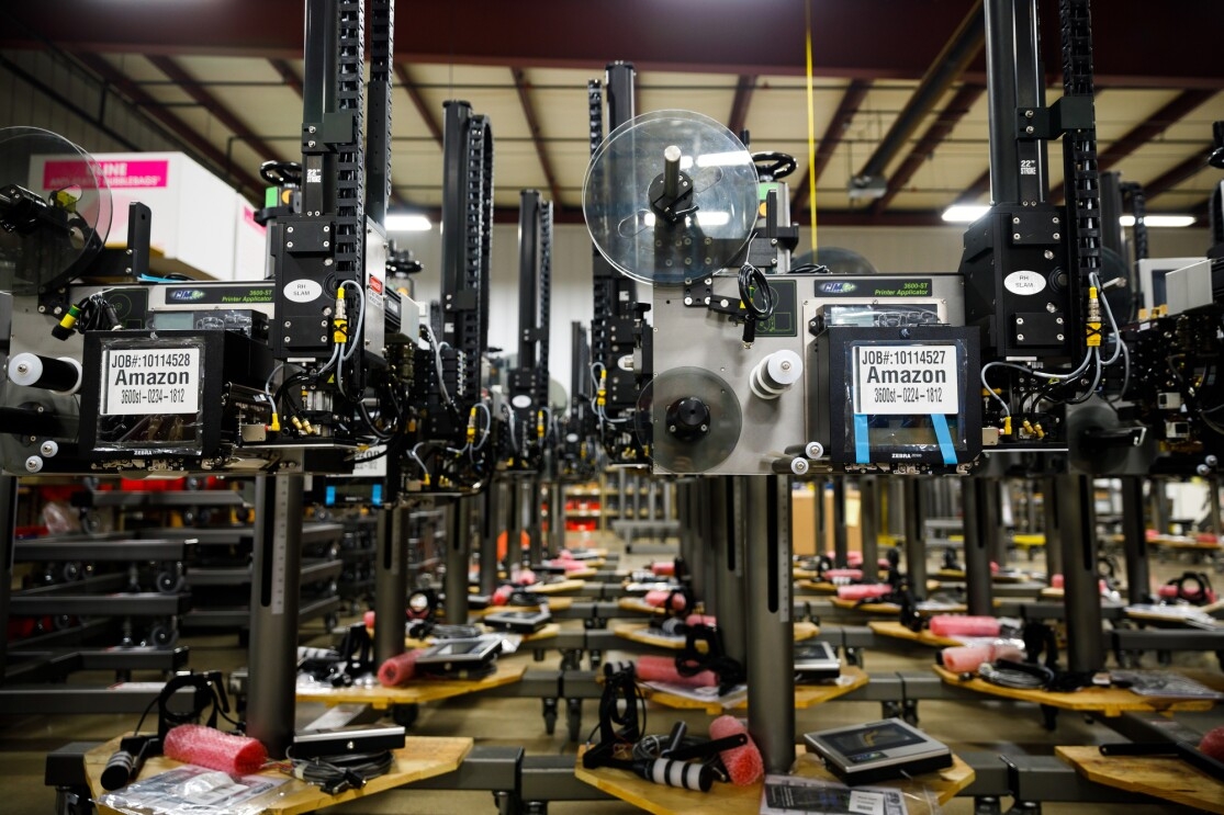 Rows of metal machines. They have labels on them that say "Amazon." A series of spools of different sizes are on the machines.