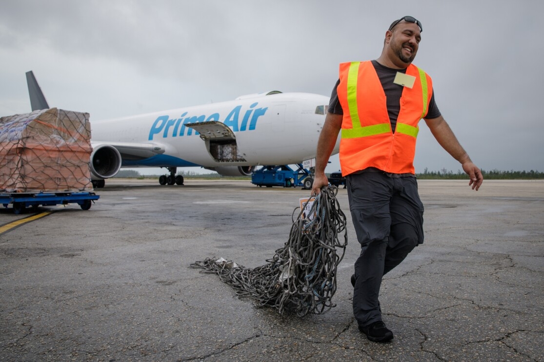 Abe Diaz of the Disaster Relief by Amazon team hauls cargo netting across the tarmac at Lynden Pindling International Airport in Nassau.