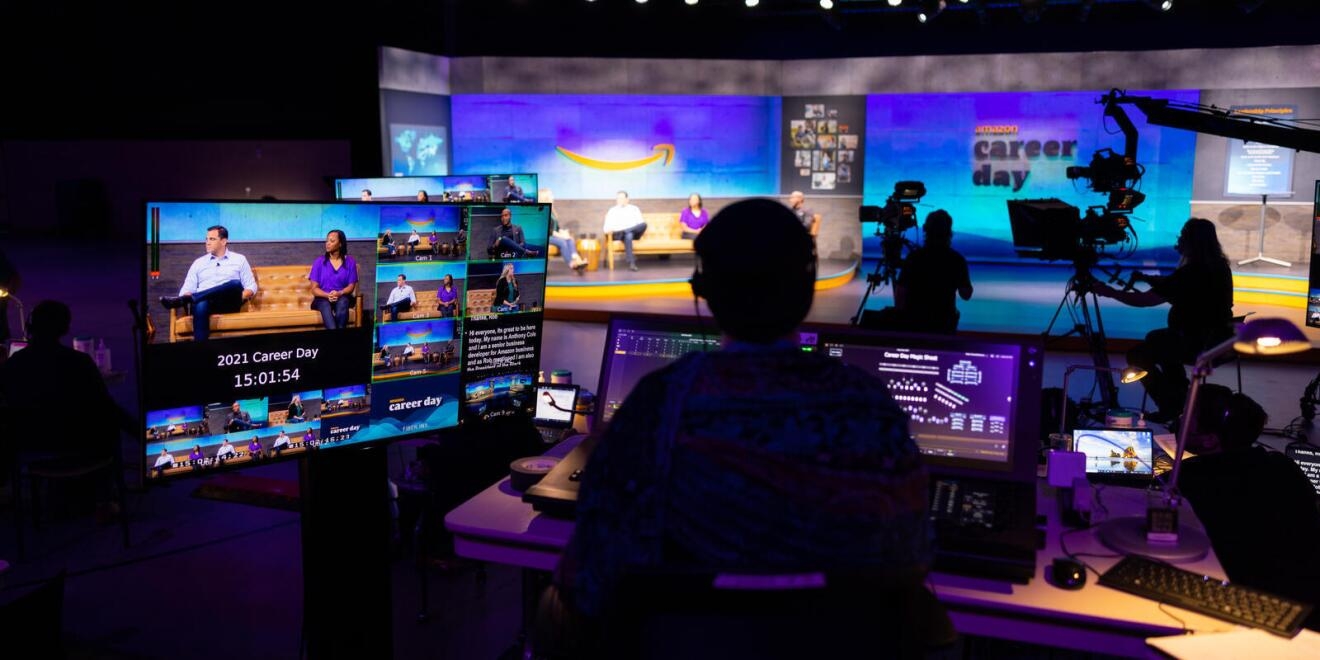 A person sitting behind a series of monitors works on Amazon Career day