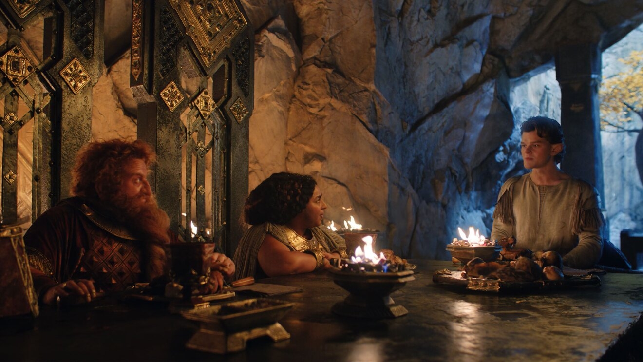 An image of Prince Durin and Princess Disa sitting at a table with Elrond in a scene from the Prime Video series, "The Lord of the Rings: The Rings of Power."