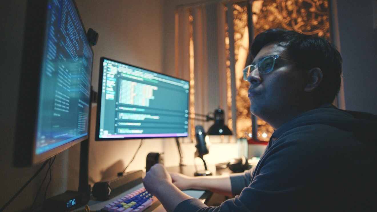 José Tapia, sitting at a desk, viewing information on two computer monitors.