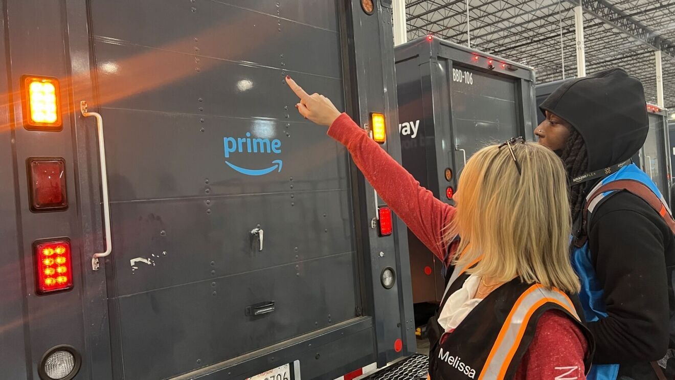 An image of a woman, an Amazon Delivery Service Partner, in a work vest standing in front of a delivery van.