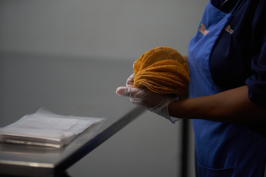 An employee packages freshly made tortillas.