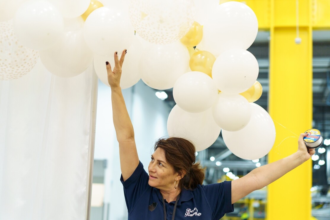 A woman holds her arm above her head and lifts decorative balloons.