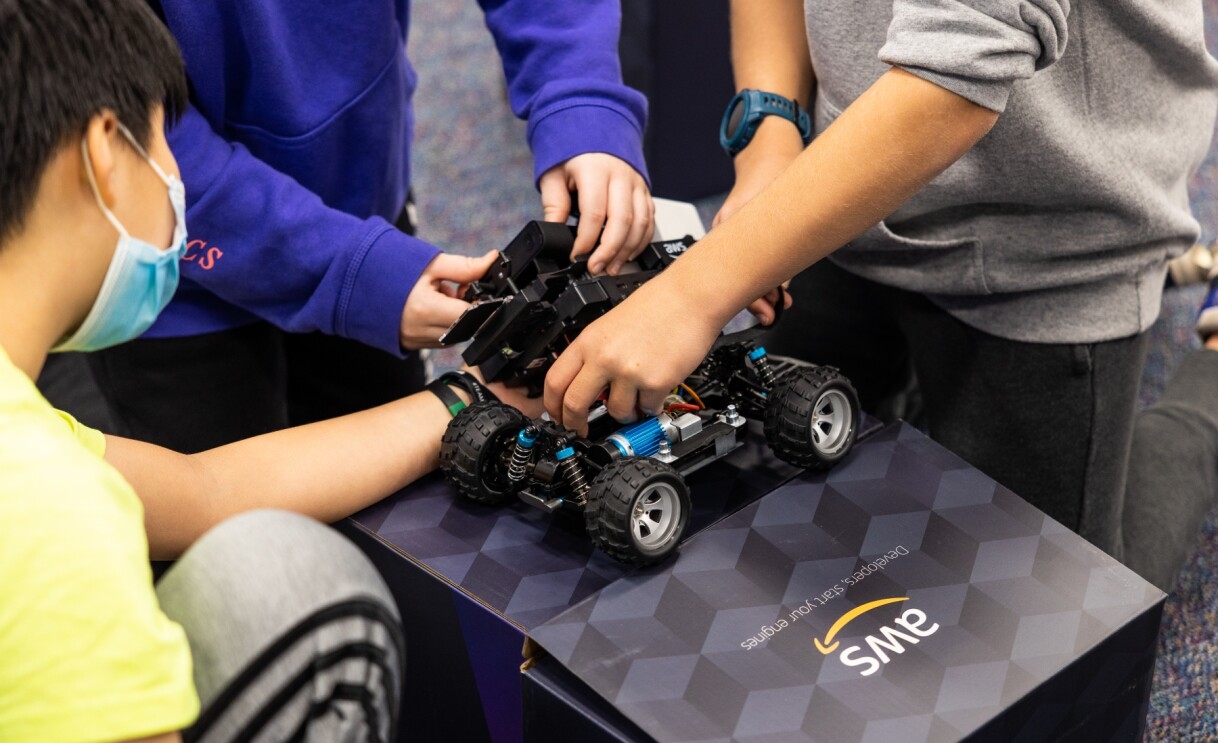 A photo of four students working on an AWS robotic car.