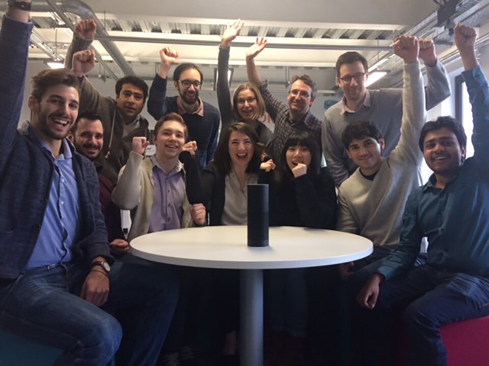 A group of students and their faculty advisor sit around a table with an Echo device on it. 