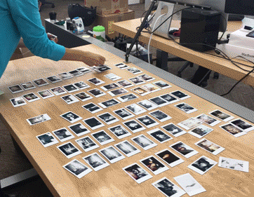 Time-lapse video of a woman picking up dozens of prints from an instant camera.