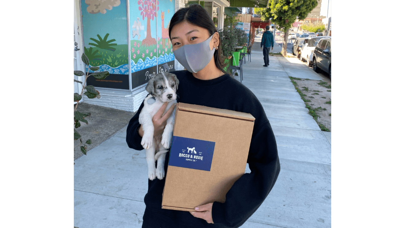 Owners hold their new adopted puppy and a Rocco & Roxie box.