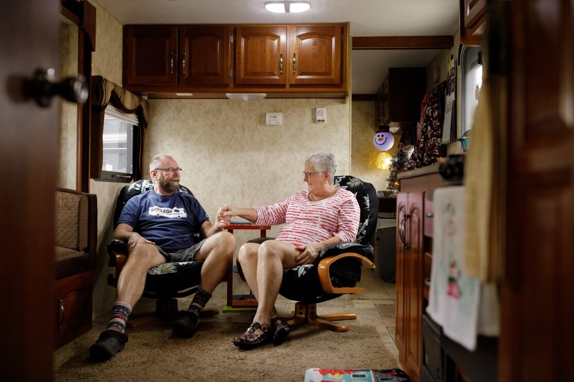 A man and woman hold hands and sit side by side.